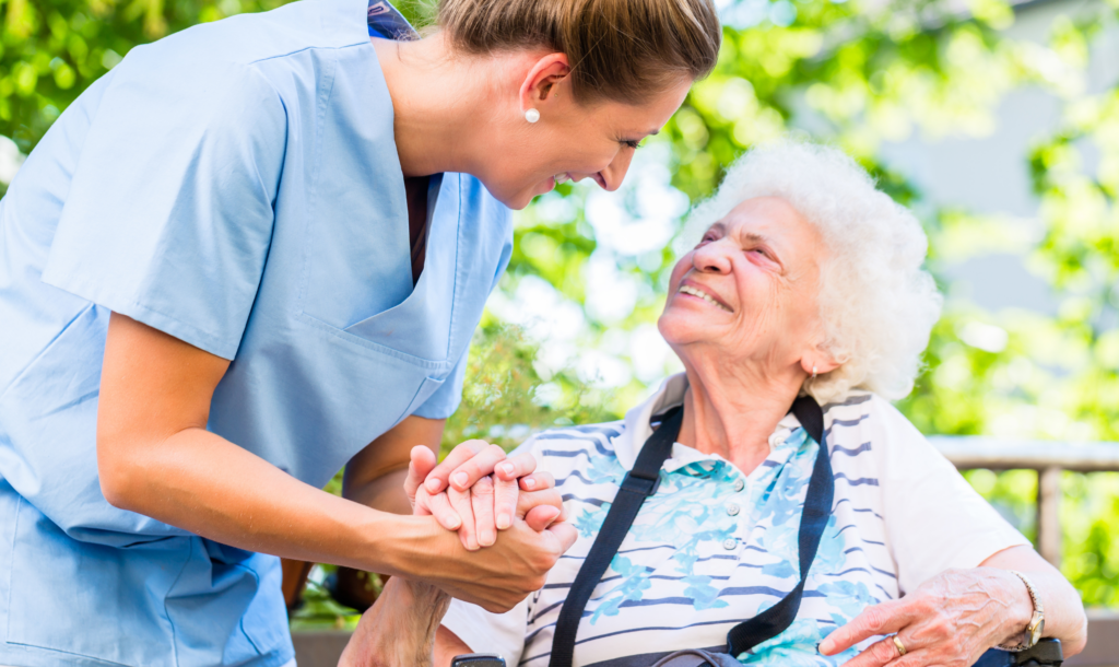 Pflegekraft hält Hand einer Seniorin
