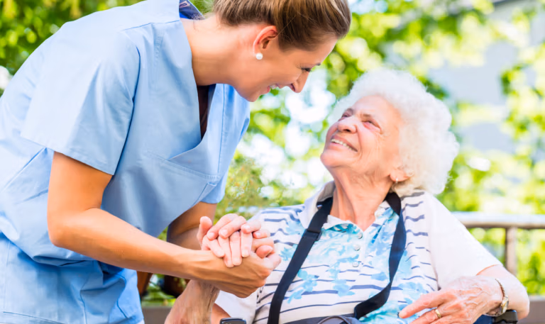 Pflegekraft hält Hand einer Seniorin