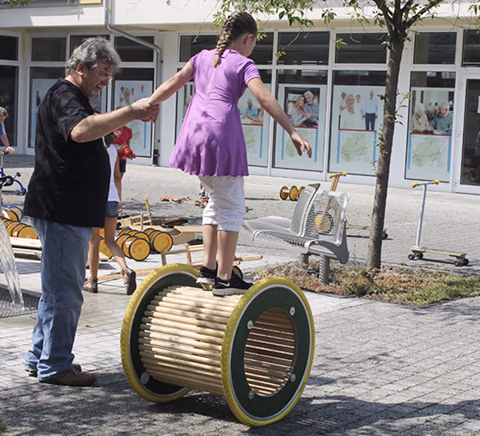 Erwachsener hilft Kind beim Balancieren auf einem Spielgerät