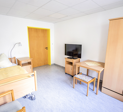 Bewohnerzimmer mit Bett und Tisch