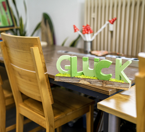 Schriftzug „Glück“ auf Holztisch