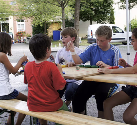 Kinder sitzen an einem Tisch und basteln gemeinsam