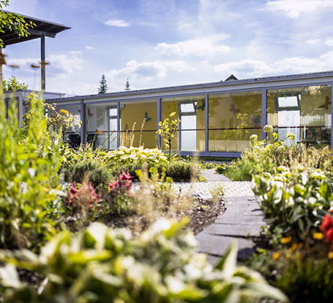 Flacher Gebäudekomplex mit Grünanlage und Blumenbeet