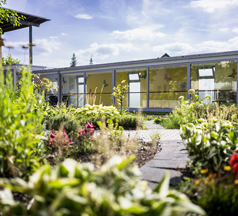 Flacher Gebäudekomplex mit Grünanlage und Blumenbeet