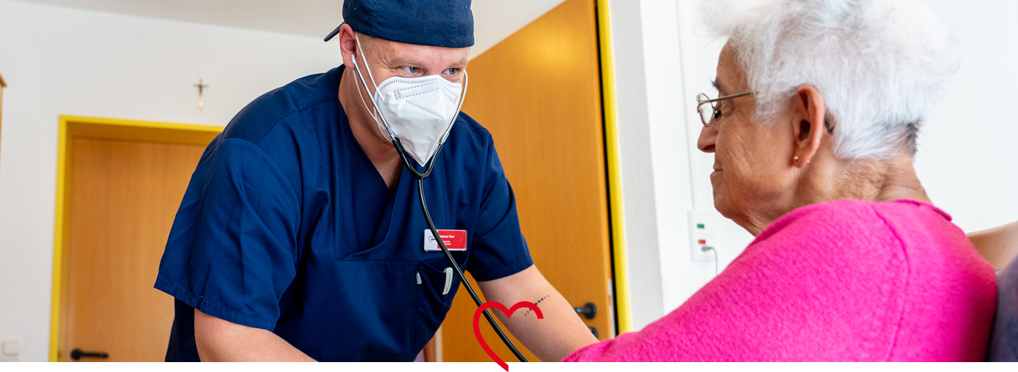 Pflegekraft mit Mundschutz misst den Puls