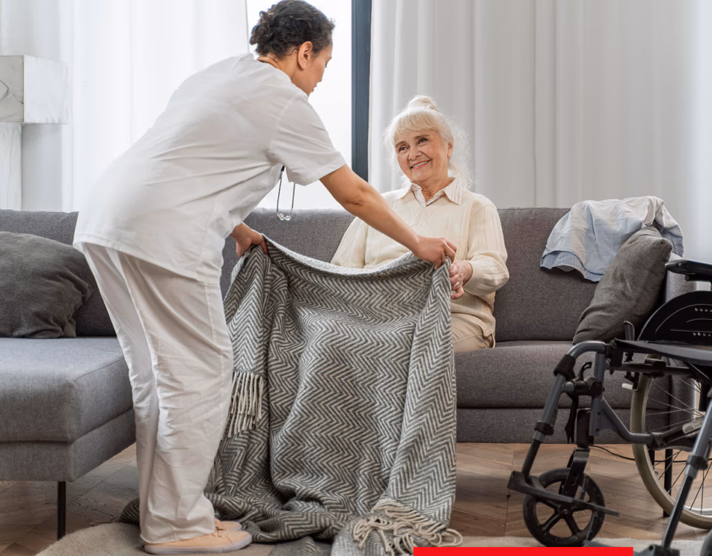Pflegekraft deckt Seniorin mit einer Decke zu