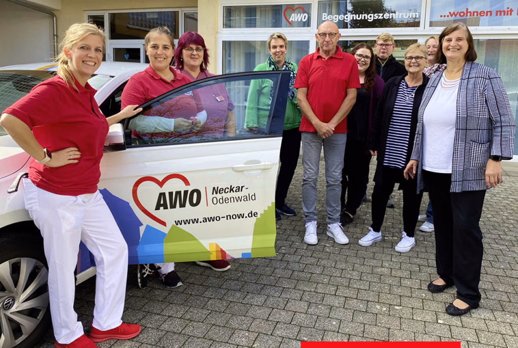 Gruppe von Menschen mit einem AWO-Fahrzeug auf Parkplatz